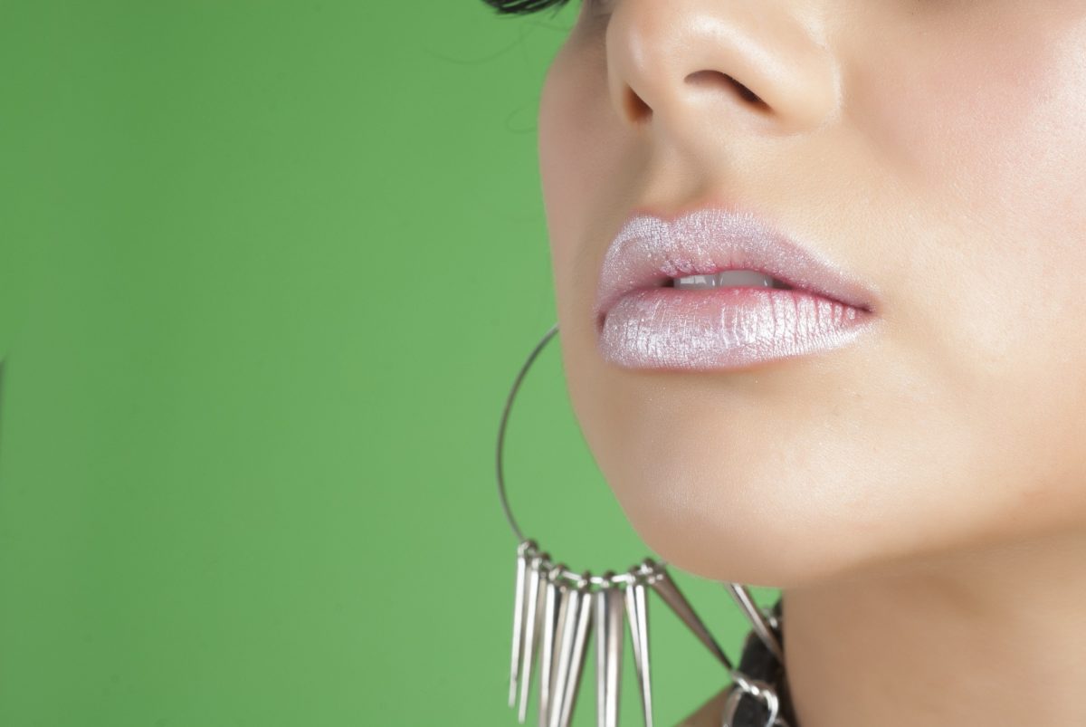 Close up of woman wearing shimmer lipstick and statement earrings