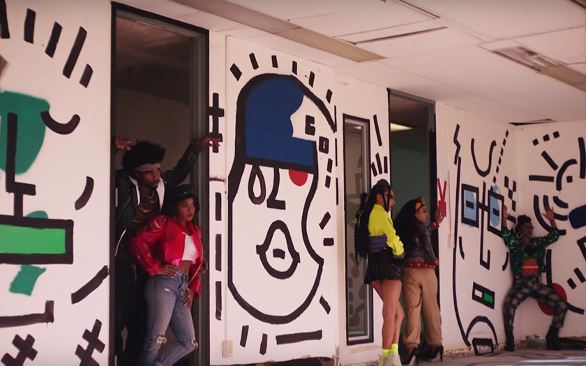 screenshot from screwed music video in an abandoned building with murals on the walls