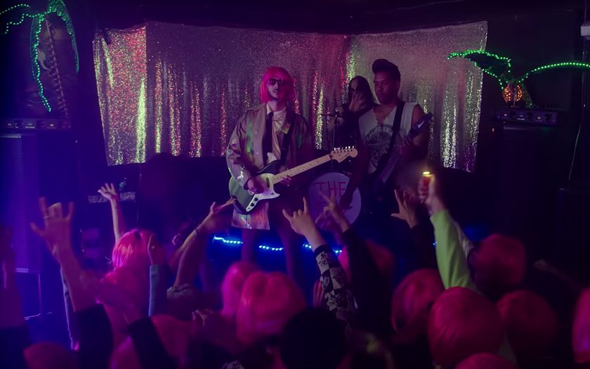 screenshot from rock music video shlomo wearing pink wig and playing electric guitar