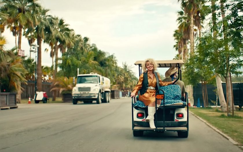 cam riding on the back of a golf cart at stagecoach festival in so long music video