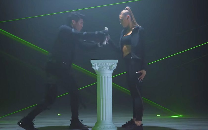 male and female dancers dance fight over scroll amid lasers