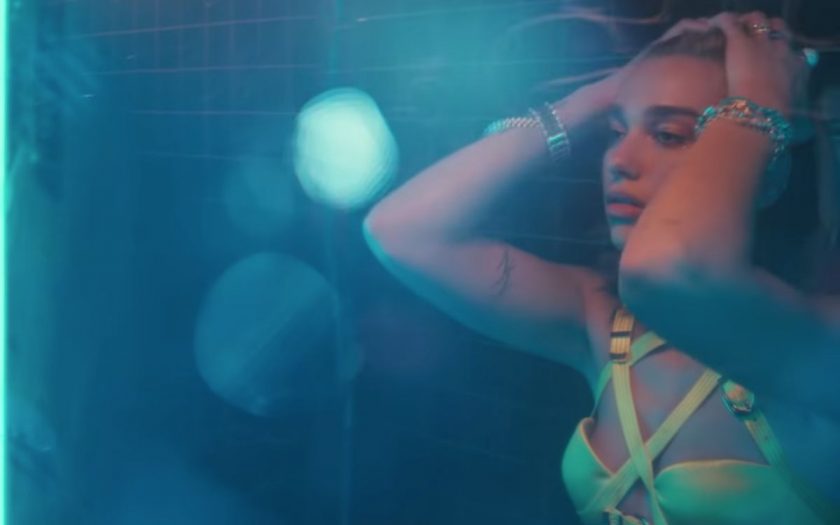 dua lipa looks at herself in the mirror in the bathroom at the club