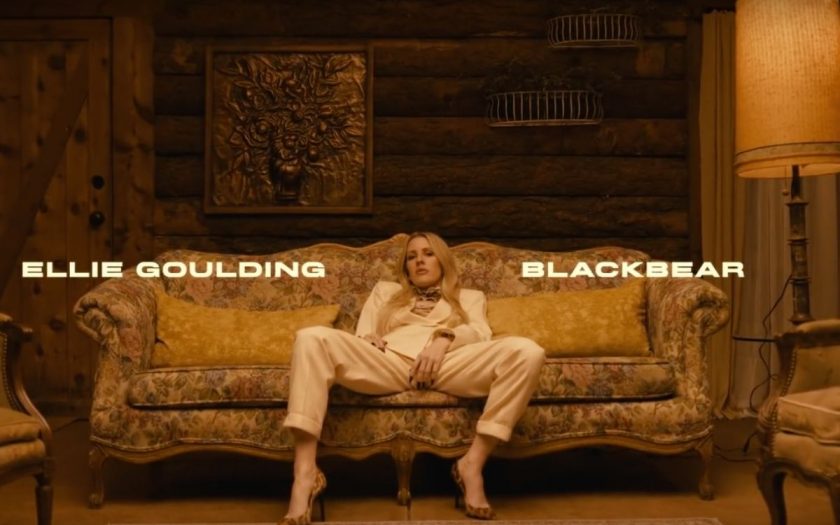 ellie goulding sitting on the couch in a wood paneled room