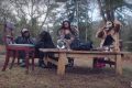 Rapper with two models and a dog at tea party in the forest